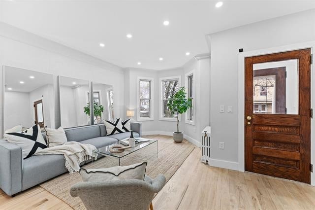 living room featuring radiator, light wood-style flooring, baseboards, and recessed lighting