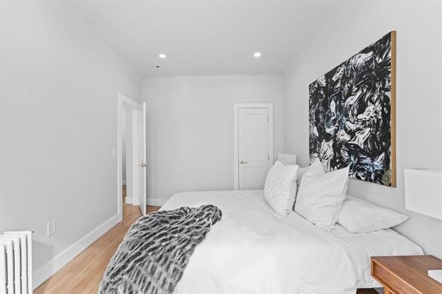 bedroom featuring light wood-style floors, radiator heating unit, baseboards, and recessed lighting