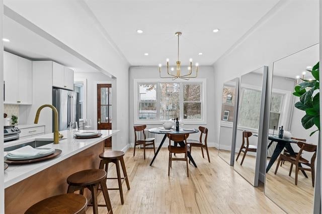 dining room featuring light wood-style floors, recessed lighting, baseboards, and an inviting chandelier