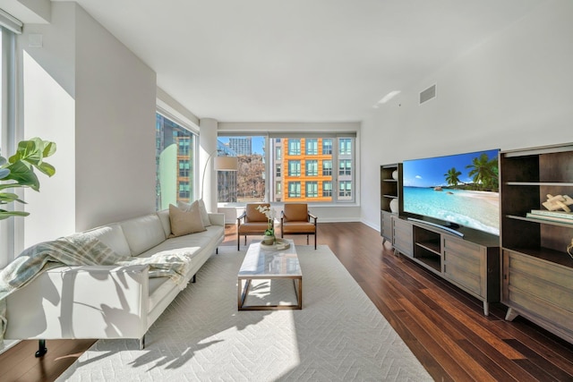 living room with wood finished floors, visible vents, and baseboards