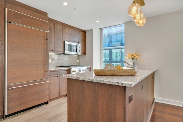 kitchen with light wood-style floors, stainless steel microwave, tasteful backsplash, and built in fridge