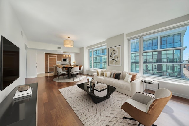 living room featuring visible vents, dark wood-style floors, and baseboards