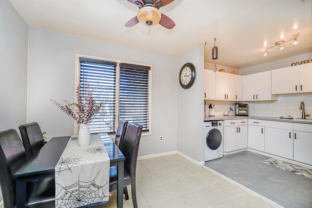 kitchen featuring baseboards, washer / clothes dryer, ceiling fan, white cabinetry, and tasteful backsplash