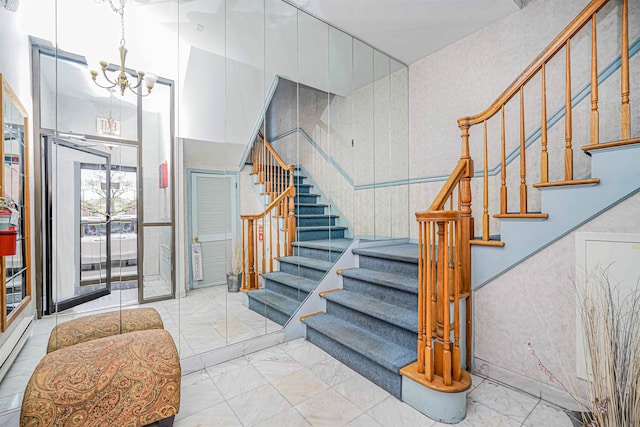 stairs featuring marble finish floor, a baseboard heating unit, and a chandelier