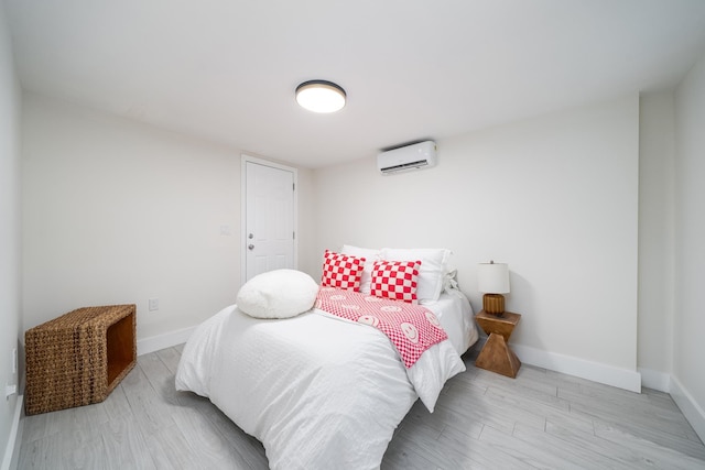 bedroom featuring an AC wall unit, baseboards, and wood finished floors