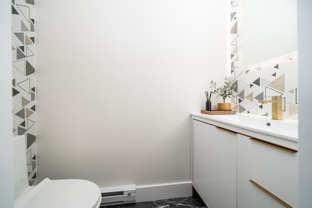 half bathroom featuring toilet, baseboards, baseboard heating, and vanity