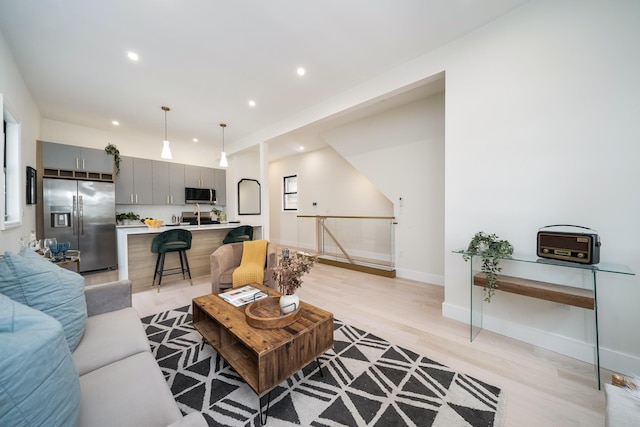 living room with baseboards, light wood finished floors, and recessed lighting