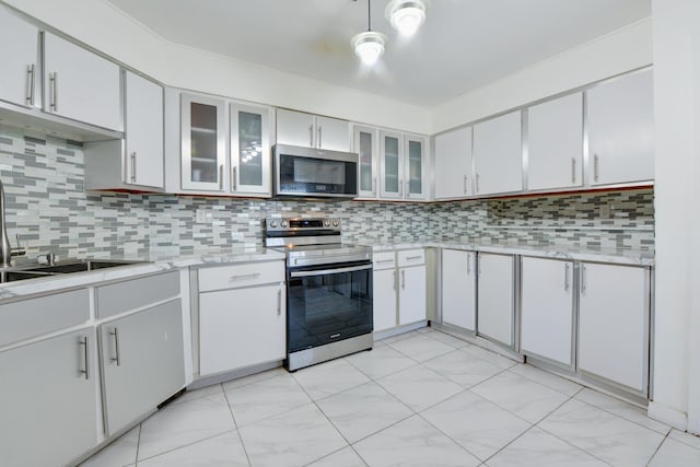 kitchen with backsplash, light countertops, a sink, stainless steel appliances, and white cabinetry