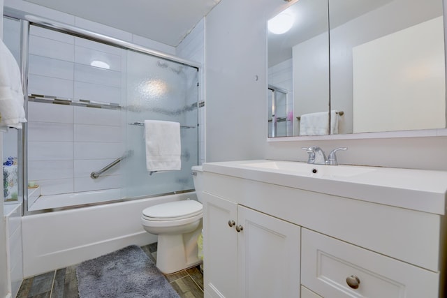 bathroom featuring toilet, enclosed tub / shower combo, wood finished floors, and vanity