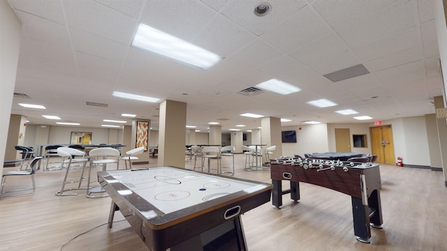 rec room with a paneled ceiling, visible vents, and wood finished floors