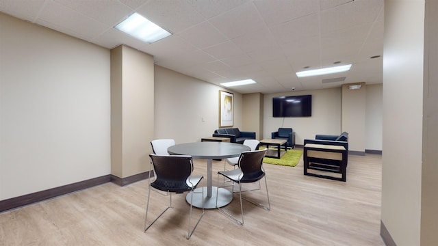 dining space with baseboards, a paneled ceiling, and light wood-style floors