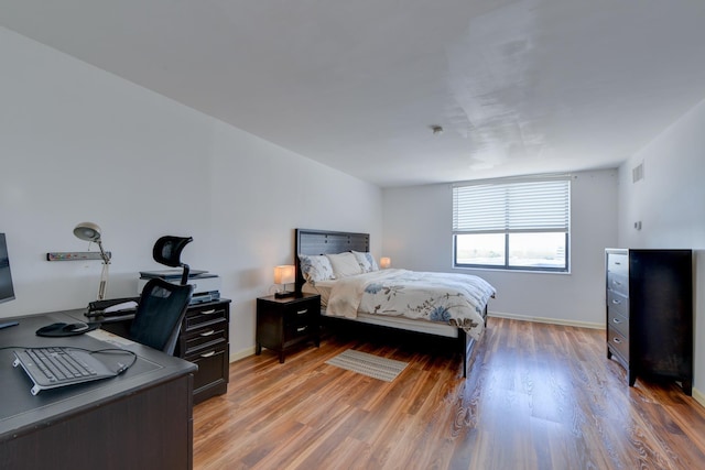 bedroom with baseboards, light wood finished floors, and visible vents