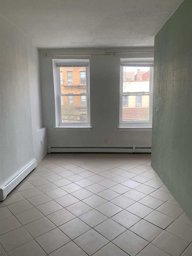 tiled spare room featuring a healthy amount of sunlight, a textured ceiling, and a baseboard radiator