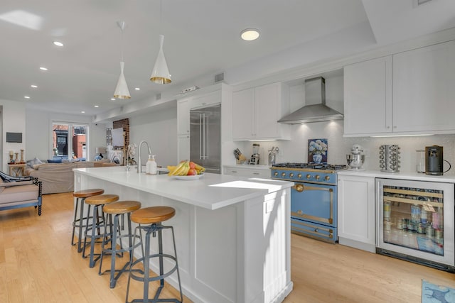 157 8th St, Hoboken, NJ 07030 - kitchen featuring wall chimney exhaust hood, high end appliances, beverage cooler, tasteful backsplash, and light wood-style flooring