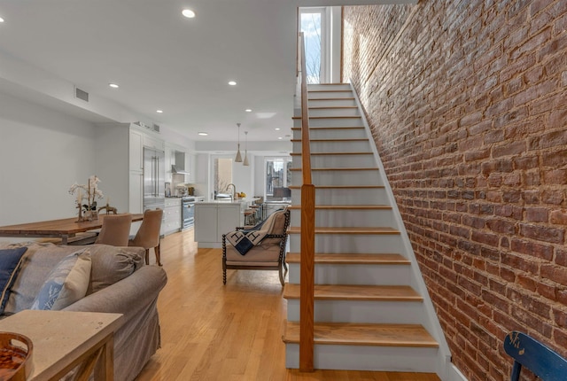 157 8th St, Hoboken, NJ 07030 - stairs featuring recessed lighting, wood finished floors, and brick wall