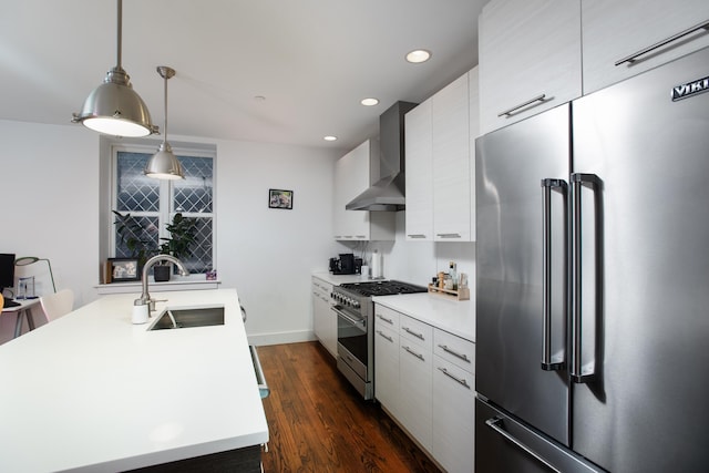 kitchen featuring wall chimney range hood, sink, hanging light fixtures, dark hardwood / wood-style floors, and high quality appliances