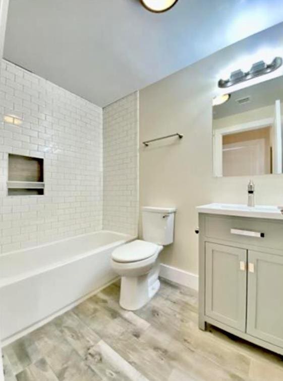 bathroom with shower / bathtub combination, vanity, toilet, wood finished floors, and baseboards