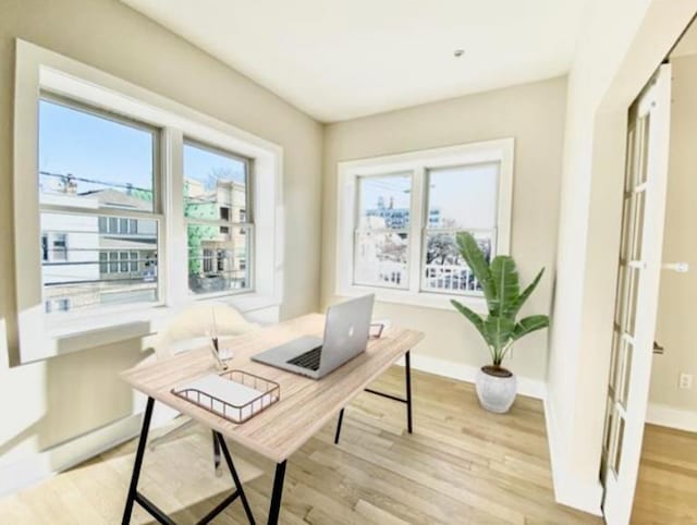 office area featuring light wood-type flooring, baseboards, and a wealth of natural light