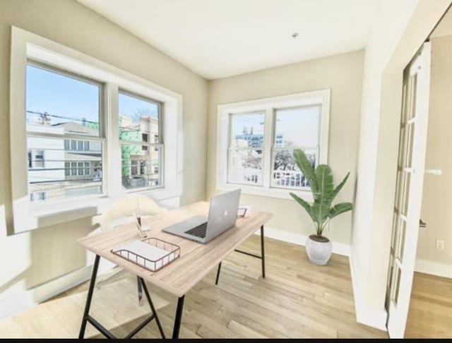 office with light wood-style flooring, baseboards, and a healthy amount of sunlight