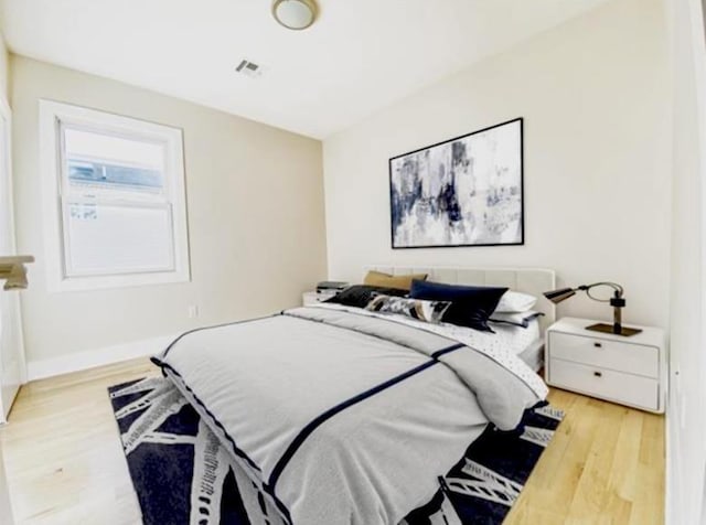 bedroom featuring wood finished floors, baseboards, and visible vents
