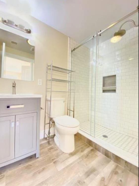 full bathroom featuring toilet, a shower stall, vanity, and wood finished floors