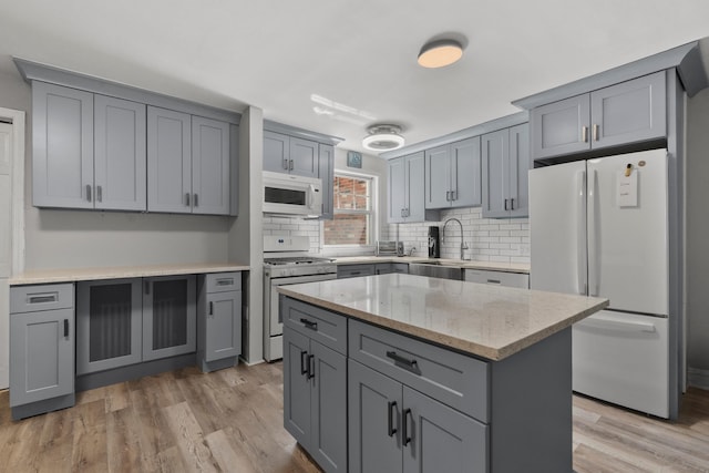 104 W 52nd St, Bayonne, NJ 07002 - kitchen featuring white appliances, gray cabinetry, backsplash, and light wood-type flooring