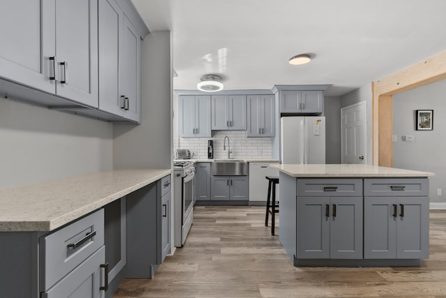104 W 52nd St, Bayonne, NJ 07002 - kitchen with white appliances, gray cabinets, tasteful backsplash, light wood-style flooring, and a center island