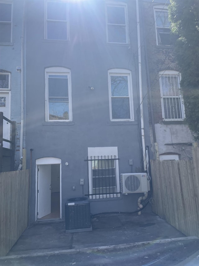 back of property featuring fence, central AC unit, ac unit, and stucco siding