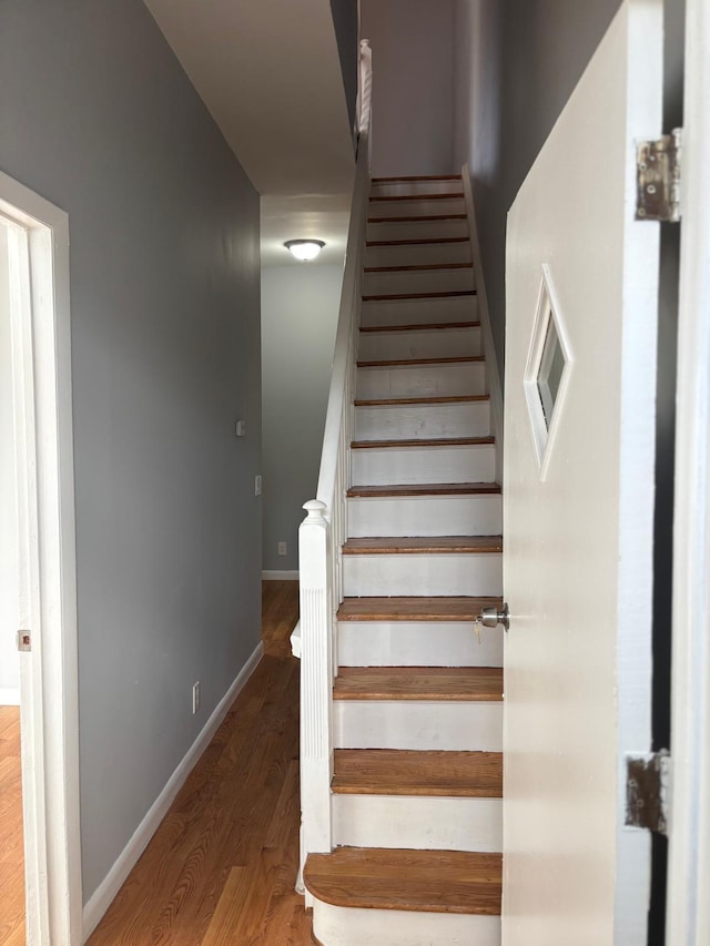 staircase with baseboards and wood finished floors