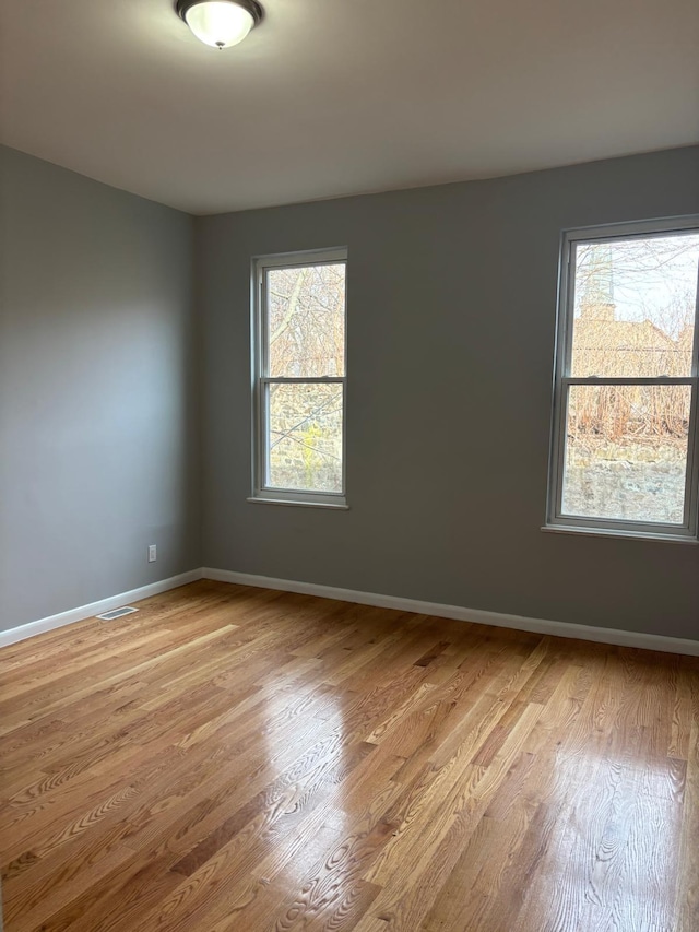 spare room featuring baseboards and light wood finished floors