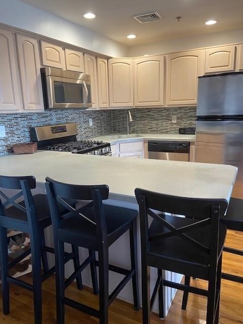 kitchen featuring appliances with stainless steel finishes, a breakfast bar, sink, and kitchen peninsula