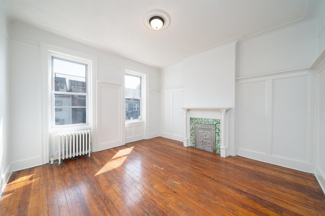 27 48th St, Weehawken, NJ 07086 - unfurnished living room featuring radiator, a decorative wall, hardwood / wood-style floors, and a tiled fireplace