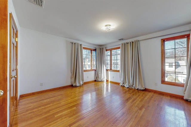 spare room featuring baseboards, visible vents, and light wood finished floors