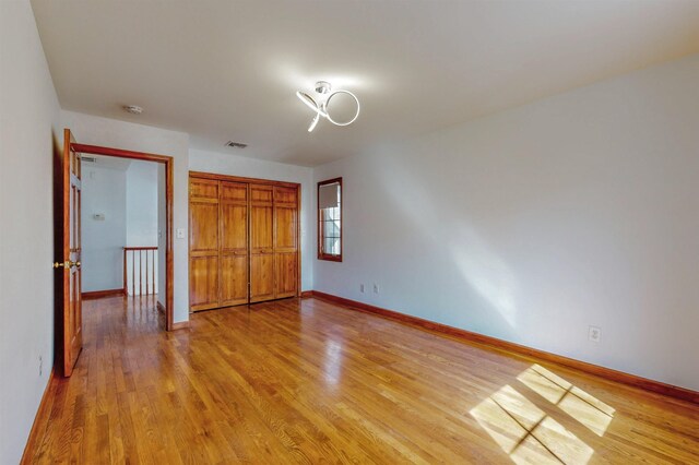 unfurnished bedroom featuring a closet, light wood-style flooring, and baseboards