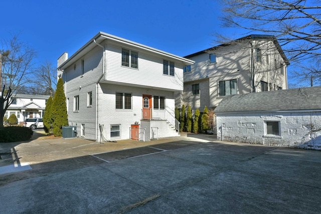 exterior space featuring brick siding, central AC unit, and a chimney