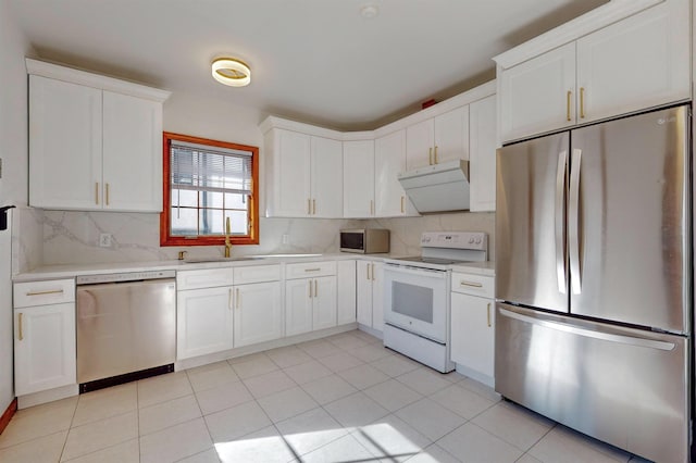 kitchen with backsplash, under cabinet range hood, light countertops, stainless steel appliances, and a sink