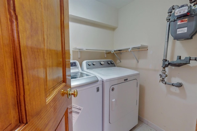 laundry room featuring light tile patterned floors, laundry area, washing machine and dryer, and baseboards