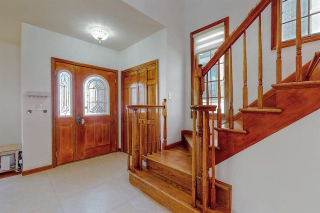 foyer entrance featuring stairway, baseboards, and light tile patterned flooring