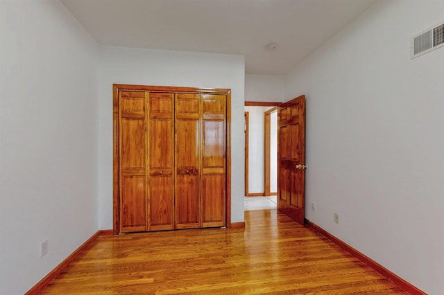 unfurnished bedroom featuring visible vents, light wood-style flooring, and baseboards