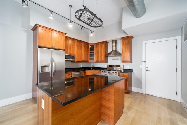 kitchen featuring appliances with stainless steel finishes, a center island, light hardwood / wood-style flooring, and wall chimney exhaust hood