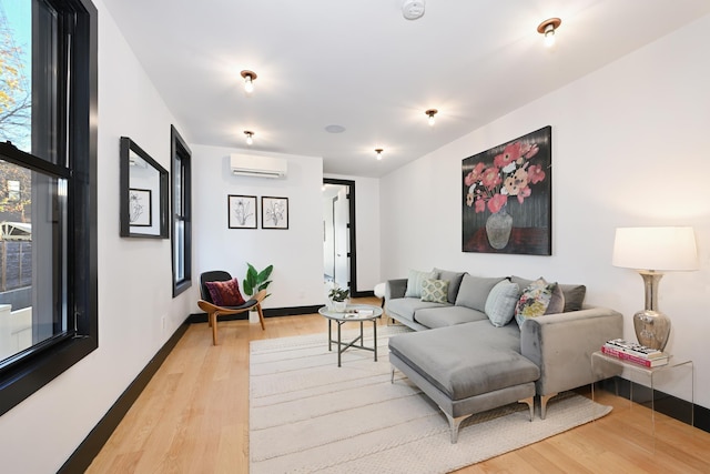 living room with a wall mounted air conditioner and light hardwood / wood-style flooring