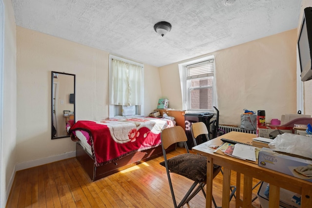 bedroom featuring a textured ceiling, hardwood / wood-style flooring, and baseboards