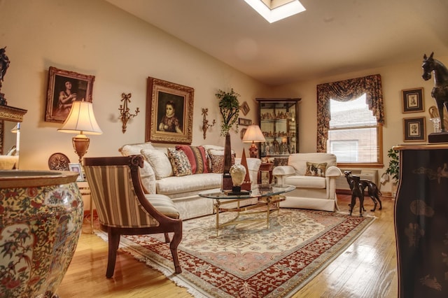 living area with vaulted ceiling with skylight and light wood-type flooring