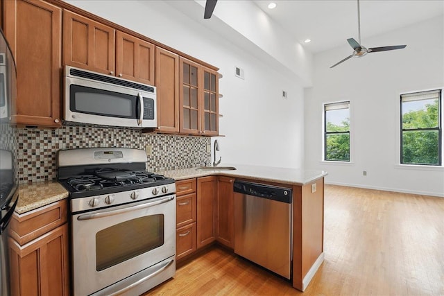 kitchen with stainless steel appliances, a ceiling fan, brown cabinets, a sink, and recessed lighting