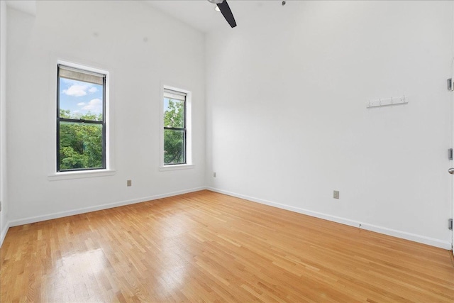 unfurnished room with light wood finished floors, a ceiling fan, and baseboards