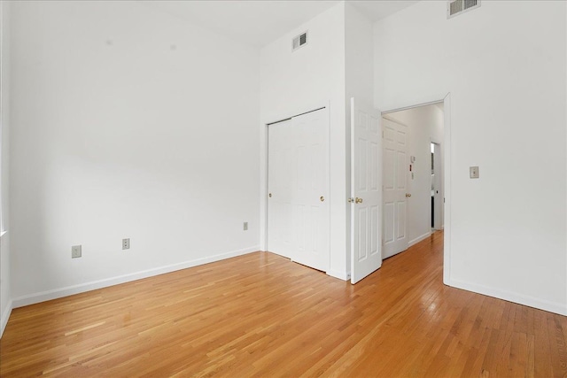 unfurnished room featuring light wood-type flooring, baseboards, and a high ceiling