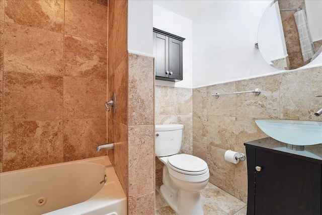 full bathroom with tile walls, toilet, vanity, a wainscoted wall, and a combined bath / shower with jetted tub