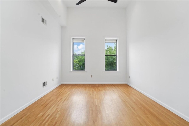 spare room featuring a ceiling fan, light wood-style floors, and baseboards