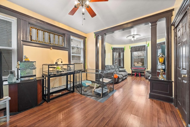 interior space with a ceiling fan, ornate columns, and wood finished floors