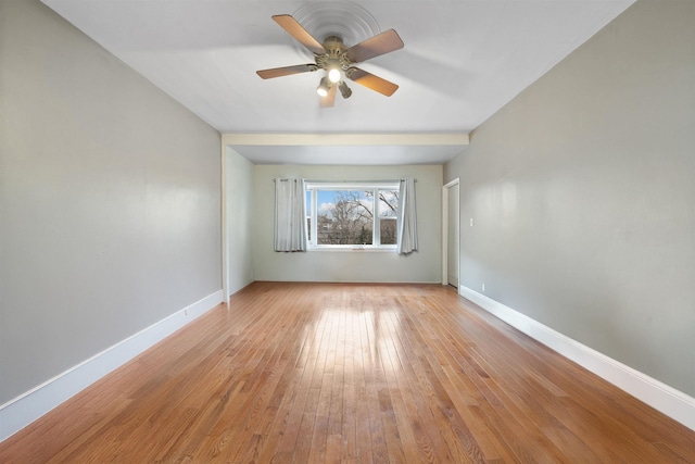 empty room with baseboards, ceiling fan, and light wood-style floors